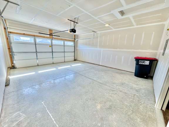A spacious garage with a ceiling fan and a red and black trash can.at Concord Crossing, Lafayette, IN
