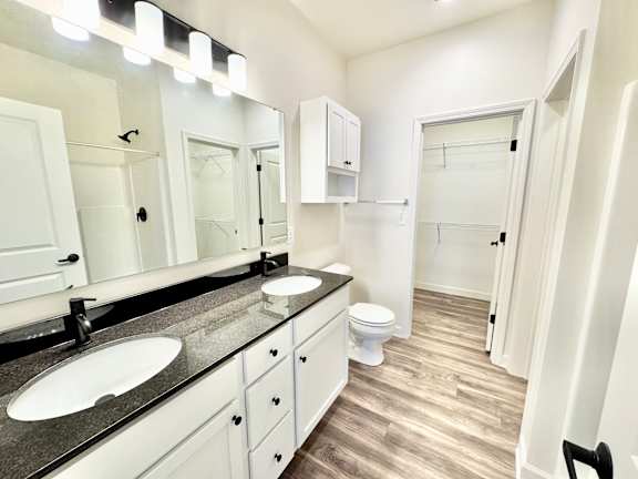 A bathroom with a sink, mirror, toilet and cupboard.at Concord Crossing, Indiana
