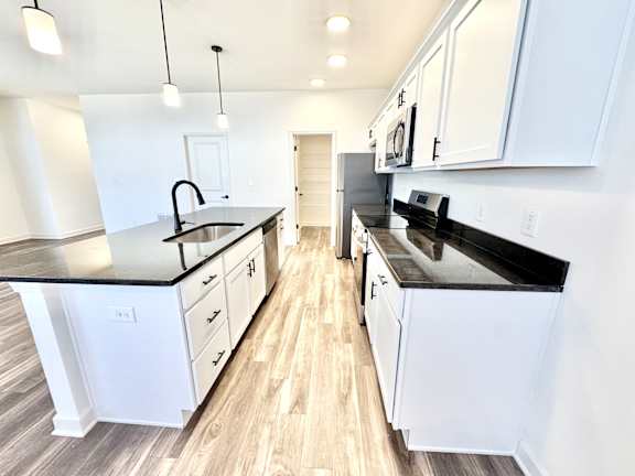 A modern kitchen with white cabinets and black countertops.at Concord Crossing, Lafayette Indiana
