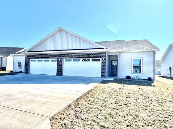 A two-car garage is attached to a white house.at Concord Crossing, Lafayette, IN 47909