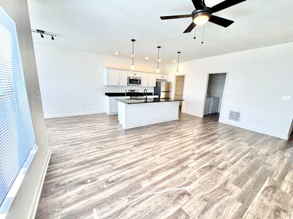 A spacious kitchen and living room with a ceiling fan and lighting fixtures.at Concord Crossing, Lafayette, IN