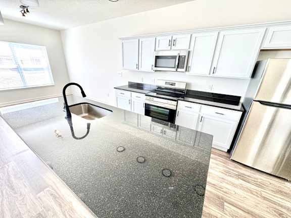 A kitchen with white cabinets and stainless steel appliances.at Concord Crossing, Indiana