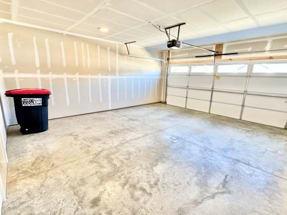 A room with a white ceiling, a black trash can, and a white garage door.at Concord Crossing, Lafayette, IN