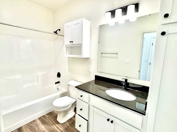 A white bathroom with a toilet, sink, and a mirror.at Concord Crossing, Indiana