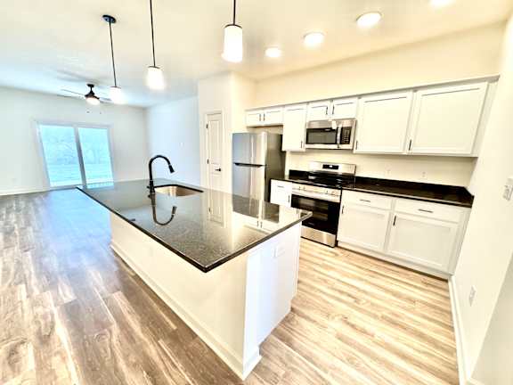 A modern kitchen with white cabinets and a black countertop.at Concord Crossing, Lafayette, 47909