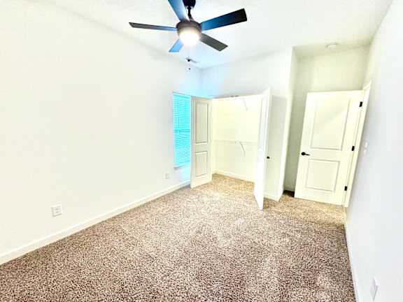 A room with a ceiling fan and carpeted floor.at Concord Crossing, Indiana, 47909