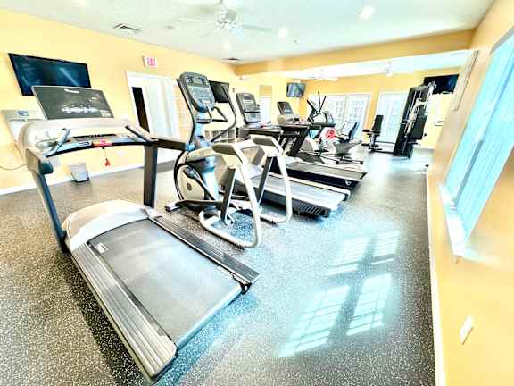 A gym with treadmills, elliptical machines, and other exercise equipment.