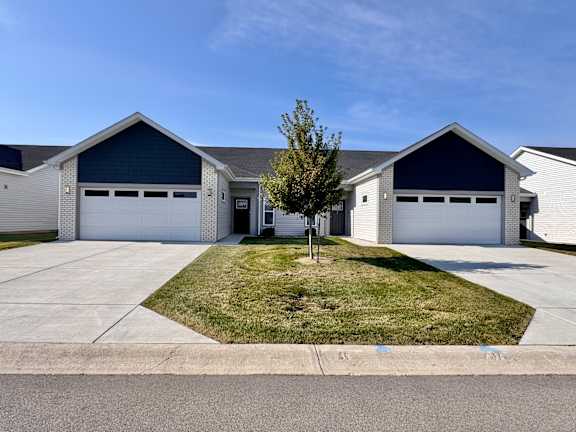 A large house with a garage and a tree in front.