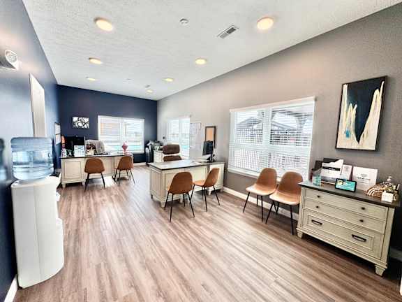 A room with a desk, chairs, and a television.