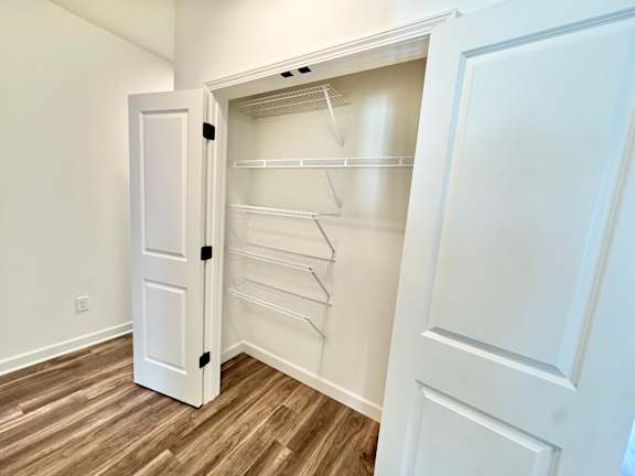 A white closet with a door open and shelves inside.