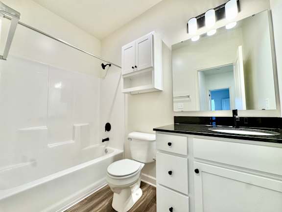 A white toilet in a bathroom with a black counter top.