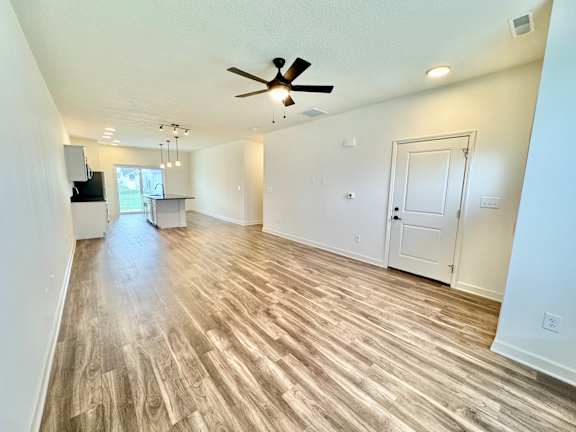 A spacious room with a ceiling fan and lighting fixtures.