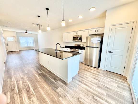 A kitchen with a stainless steel refrigerator and a white island.