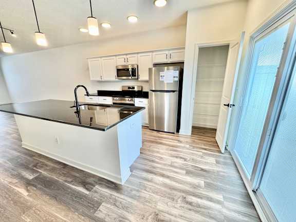 A kitchen with a black countertop and stainless steel appliances.