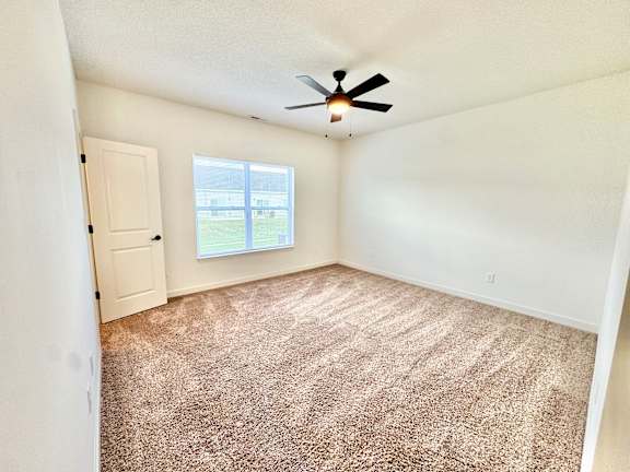 A room with a ceiling fan and carpeted floor.