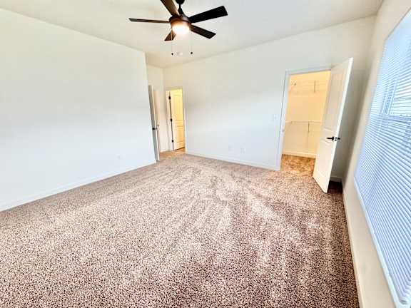 A room with a ceiling fan and carpeted floor.