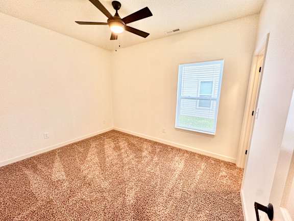 A room with a ceiling fan and a window with blinds.