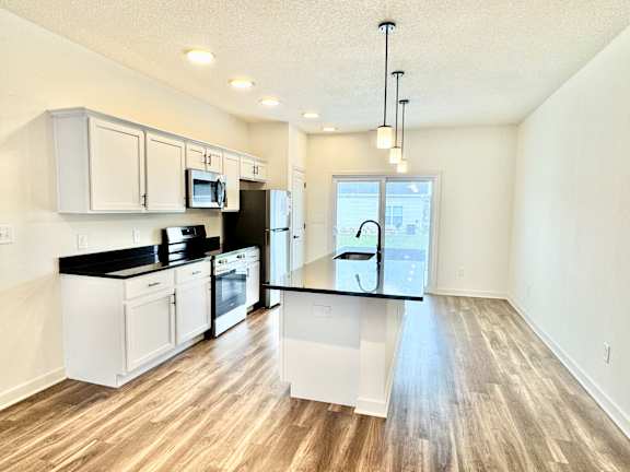 A kitchen with white cabinets and black countertops.
