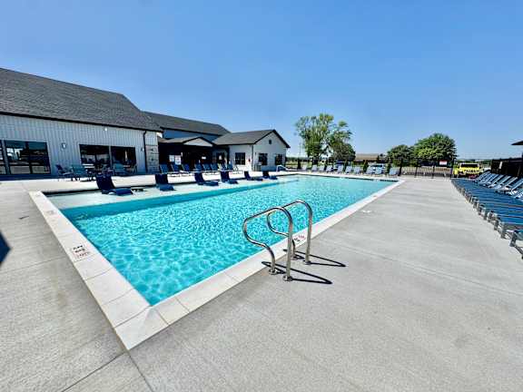 A large outdoor swimming pool with a diving board and lounge chairs.