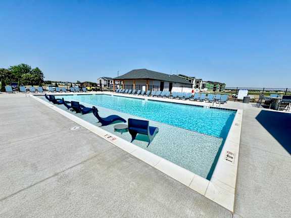 A large outdoor swimming pool with blue water and lounge chairs.