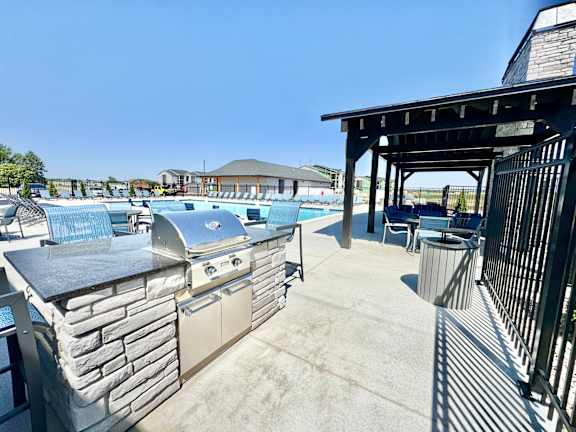 A barbecue grill is on a patio with a pool table and a table tennis table.