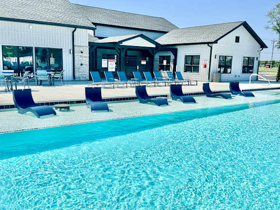 A pool with blue water and chairs around it.