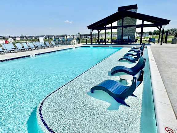 A pool with blue chairs and a black roof.