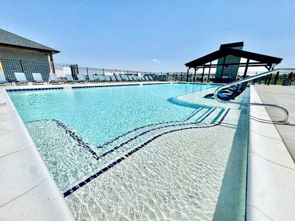 A large swimming pool with a diving board and lounge chairs.
