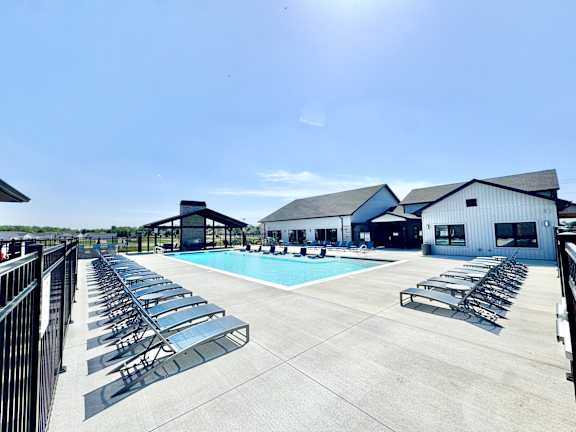 A sunny day at the pool with lounge chairs and a clear blue sky.