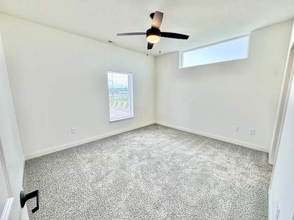 A room with a ceiling fan and carpeted floor.