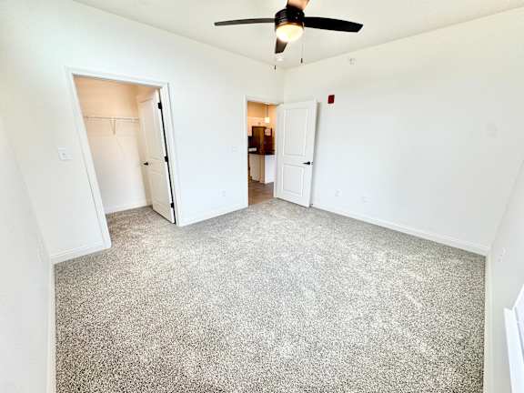 A room with a ceiling fan and carpeted floor.