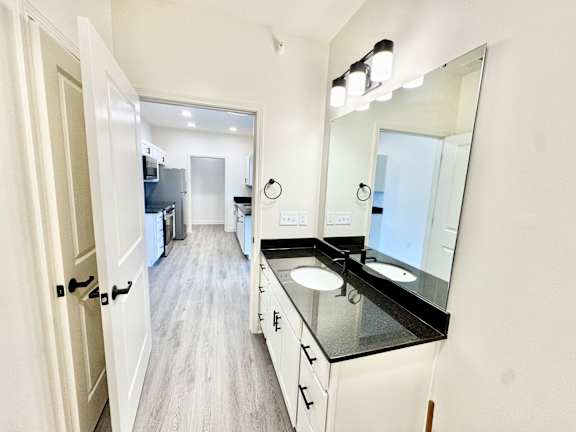 A bathroom with a sink, mirror, and a door.
