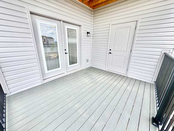 A white wooden deck with a sliding glass door and a white door.