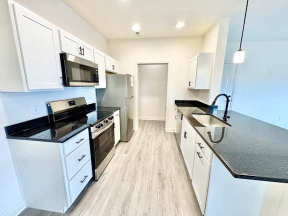 A kitchen with white cabinets and black countertops.