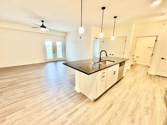 A spacious kitchen with a black countertop and white cabinets.