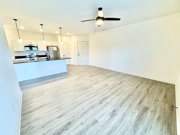 A spacious kitchen with a ceiling fan and pendant lights.