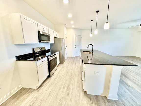 A kitchen with white cabinets and black countertops.