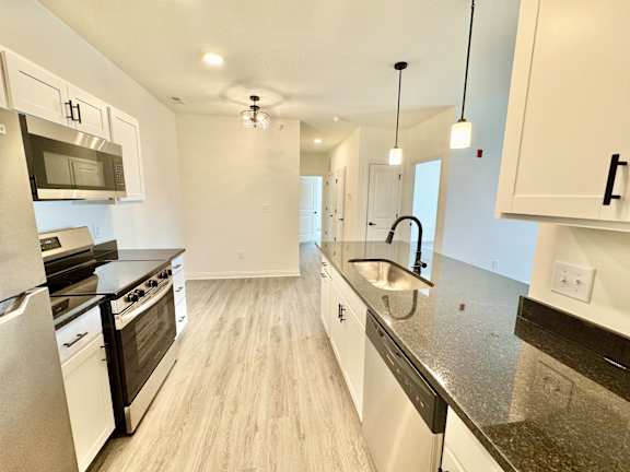 A modern kitchen with white cabinets and stainless steel appliances.