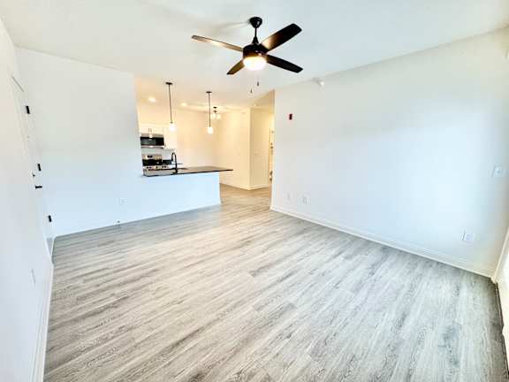 A room with a ceiling fan and wooden flooring.