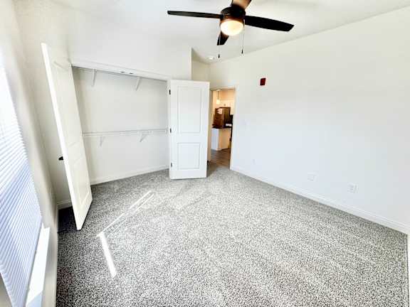 A room with a ceiling fan and a carpeted floor.