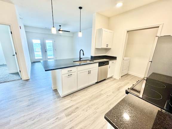 A kitchen with white cabinets and a black countertop.