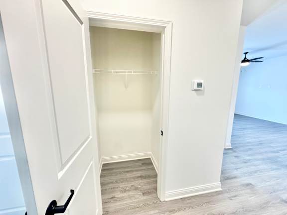 A white door is open to a room with a fan on the wall.