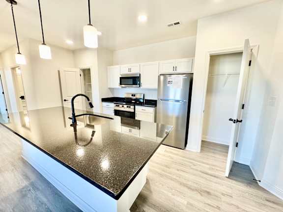 A modern kitchen with a granite countertop and stainless steel appliances.