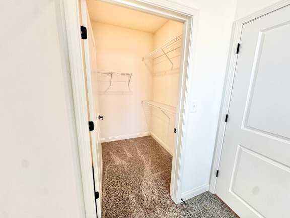 A white door is open to a small, empty room with a carpeted floor.