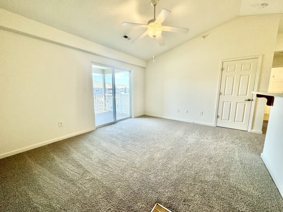 an empty living room with a ceiling fan and a door to a balcony at Hawthorne Properties in Lafayette, IN 47905
