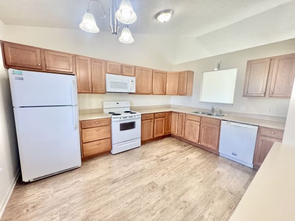 an empty kitchen with white appliances and wooden cabinets at Hawthorne Properties in Lafayette, IN 47905