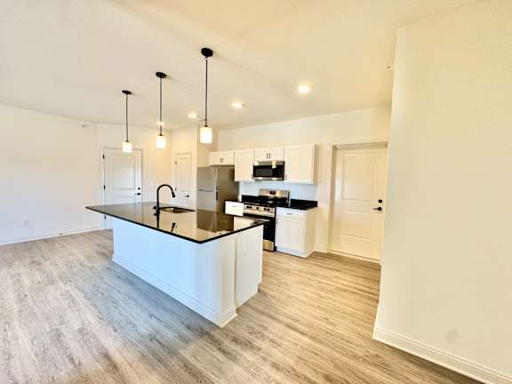 A kitchen with a black countertop and white cabinets.
