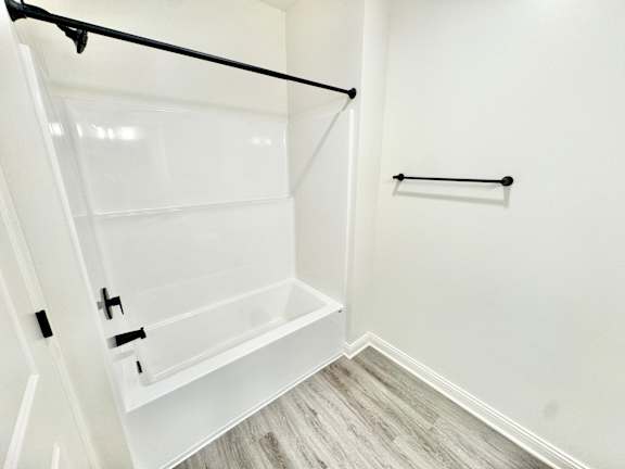 A white walk-in closet with a black rod and a white door.