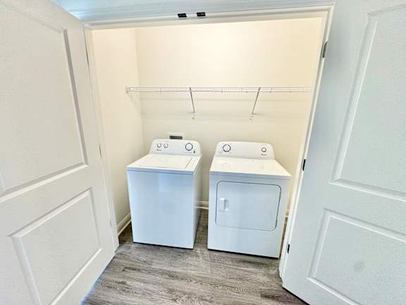 A laundry room with two washers and a shelf.