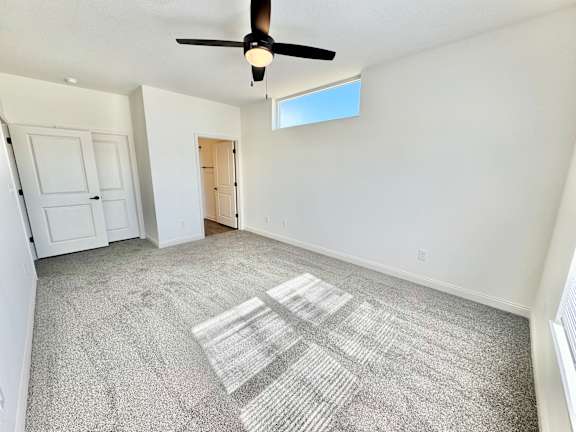 A room with a ceiling fan and carpeted floor.